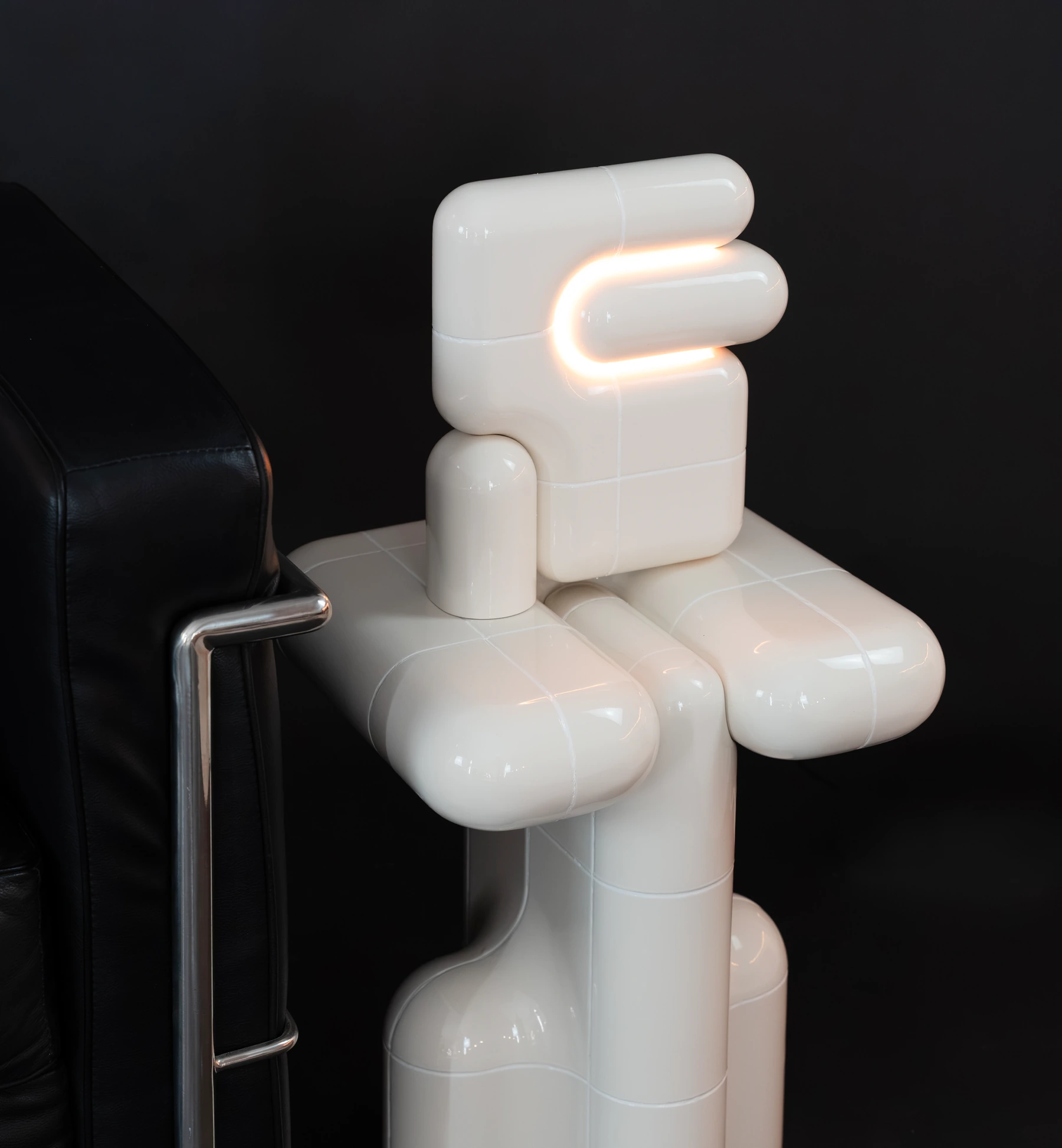 U·021 lamp on a U·001 side table in high gloss, beside a black leather armchair