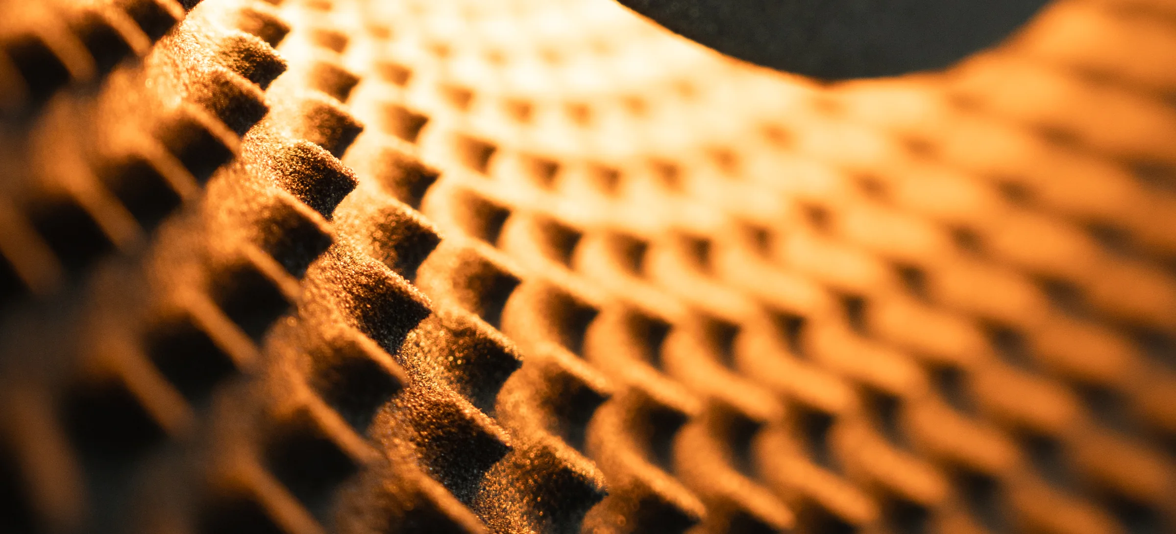 Black quartz sand, close up: the ridges of a Sun VXS wall light, lit from within